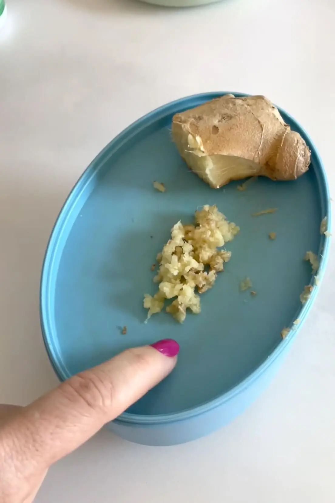 Freshly grated ginger on a blue lid, used for natural remedies to fight inflammation and support digestion.